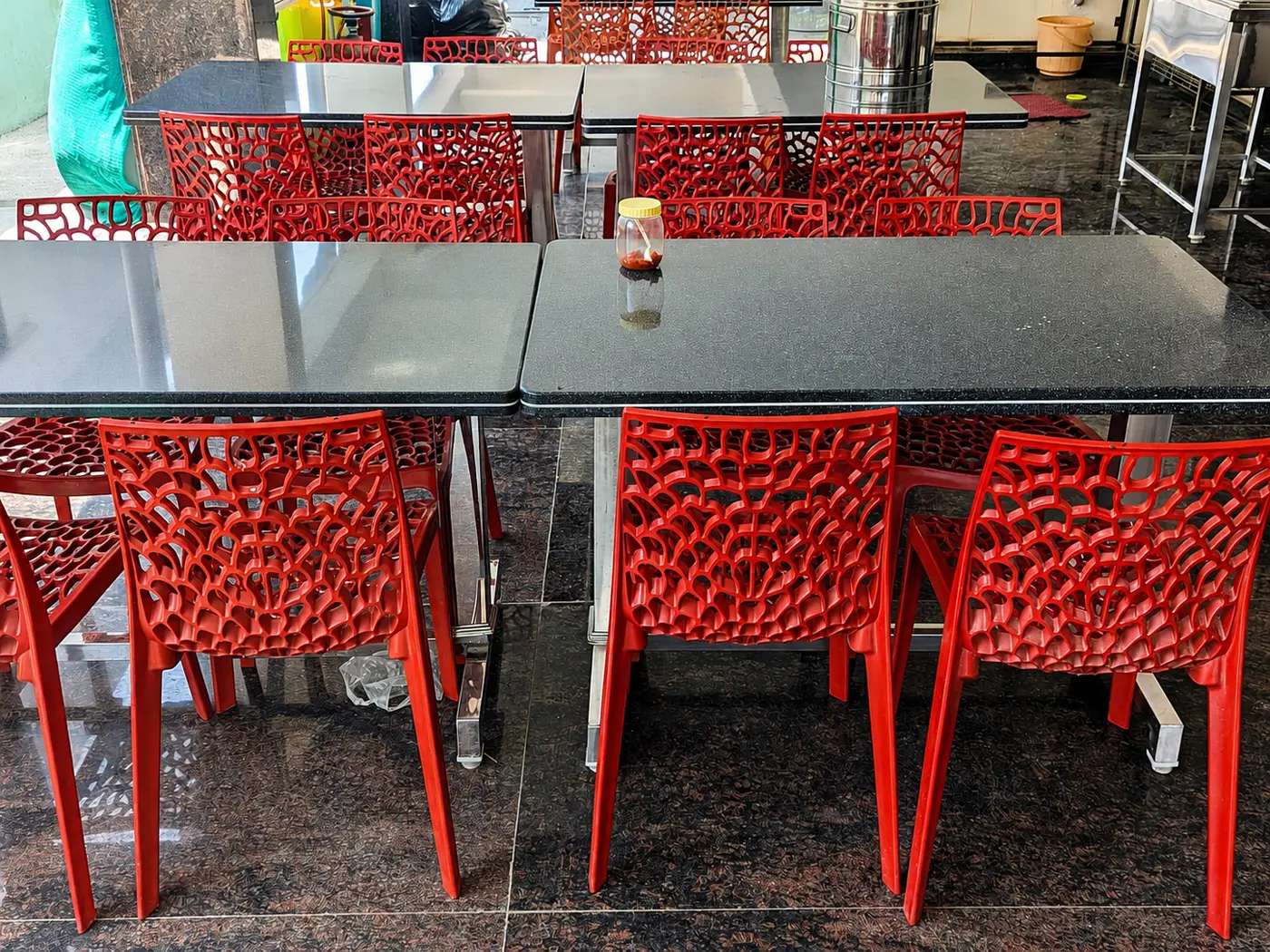 Granite-topped dining tables with red chairs in the common dining area