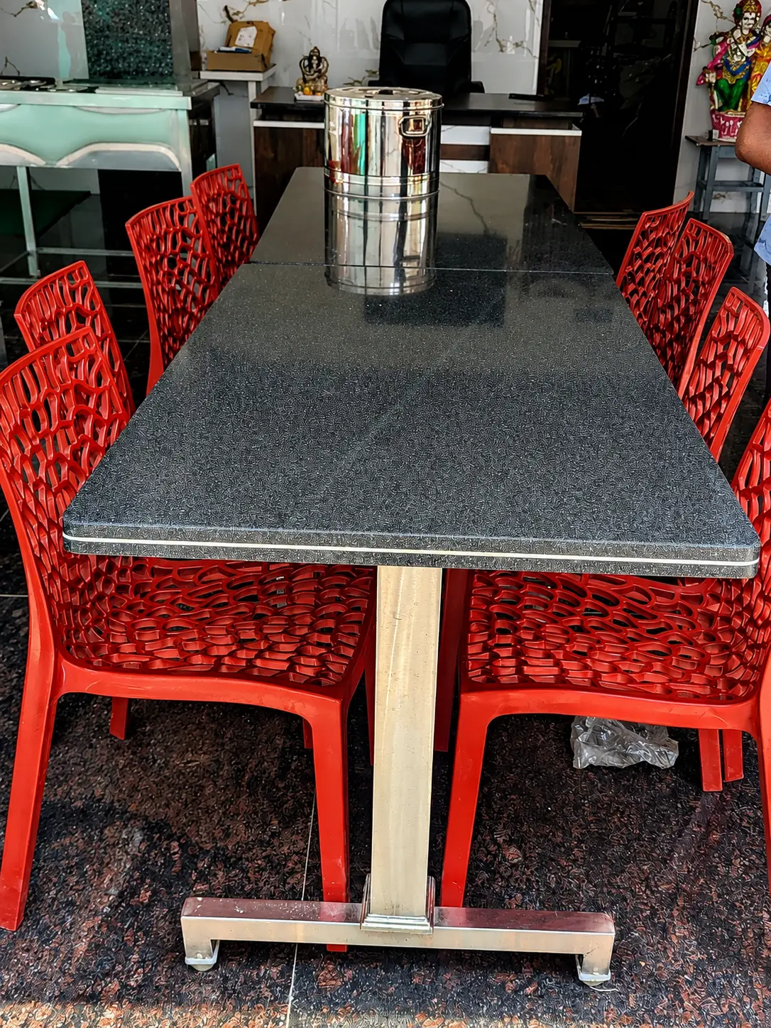 A granite dining table with red chairs drawn up around it
