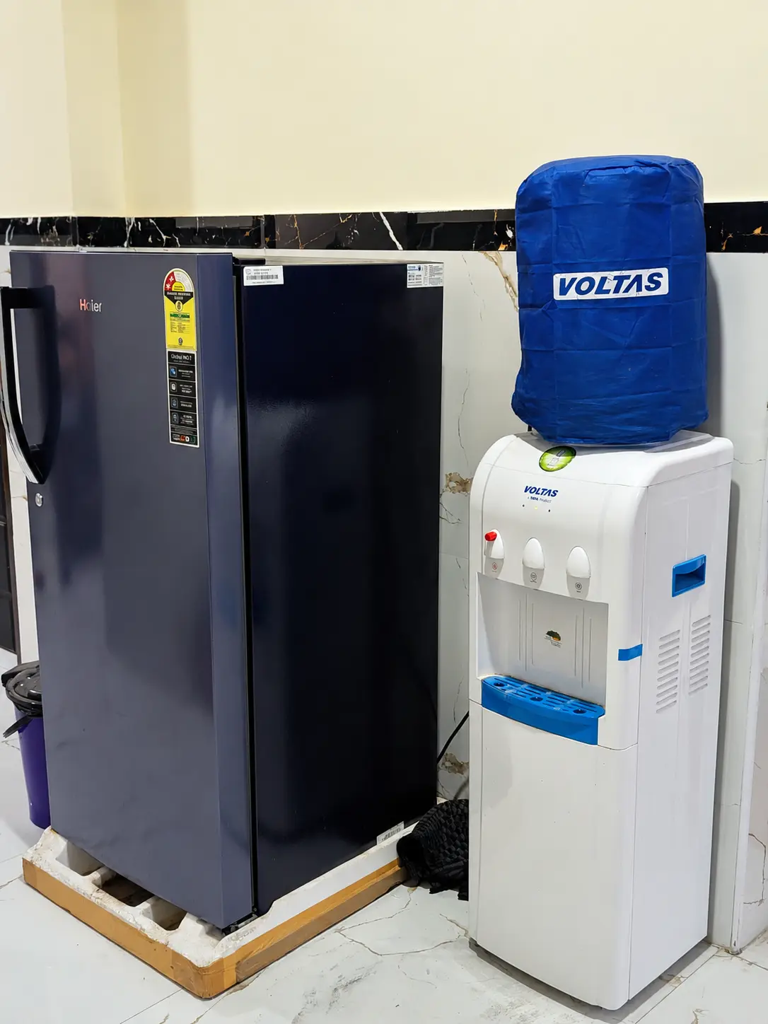 A refrigerator beside a water purifier with cold and normal water taps