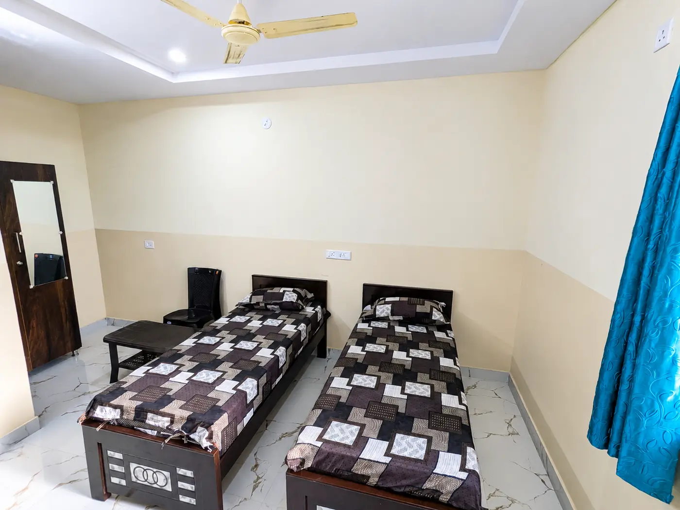Two single beds with a mirror and curtained window in a twin-sharing room