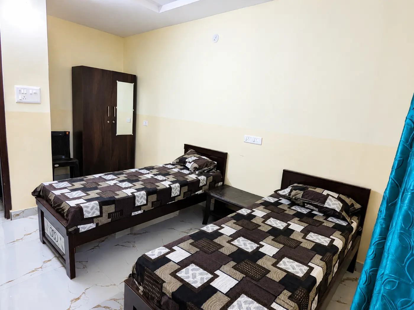 Twin beds either side of a wooden wardrobe in a tiled room